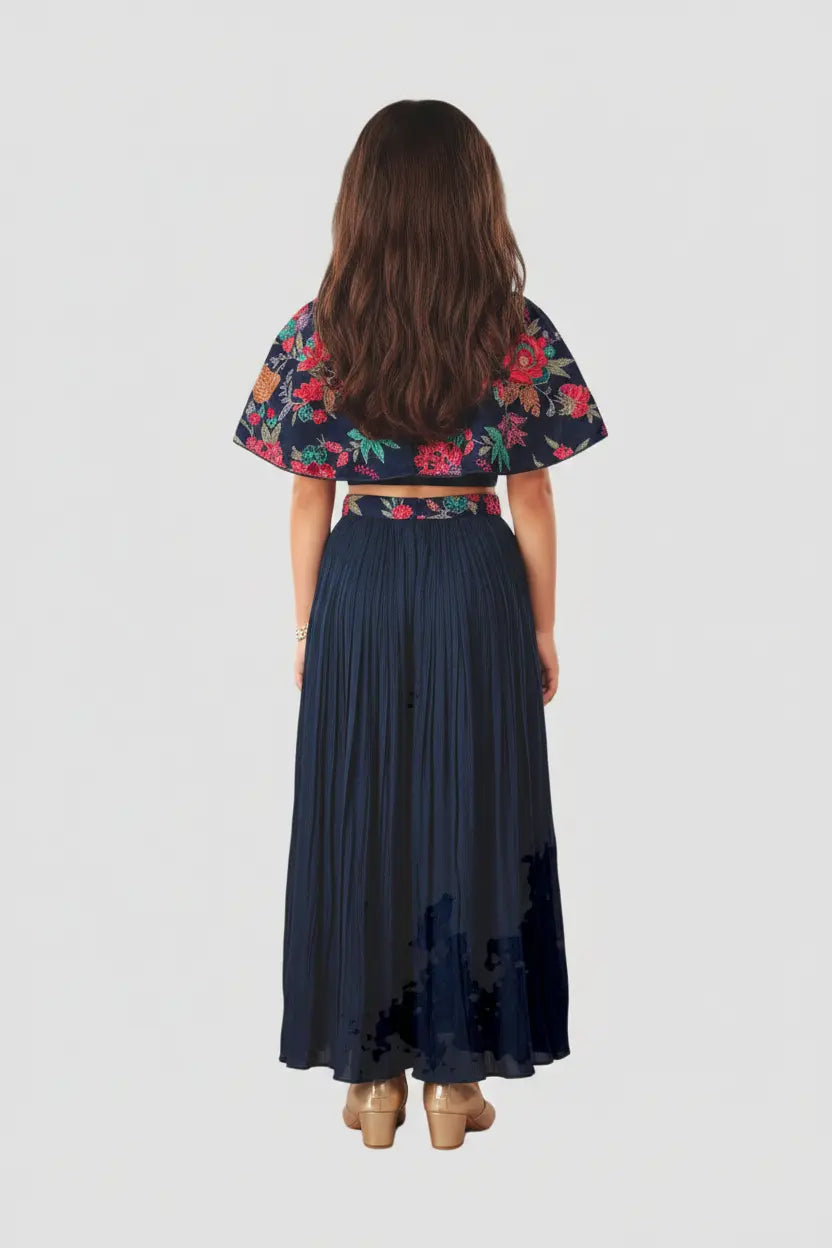 Woman wearing a floral top and navy pleated skirt on a white background