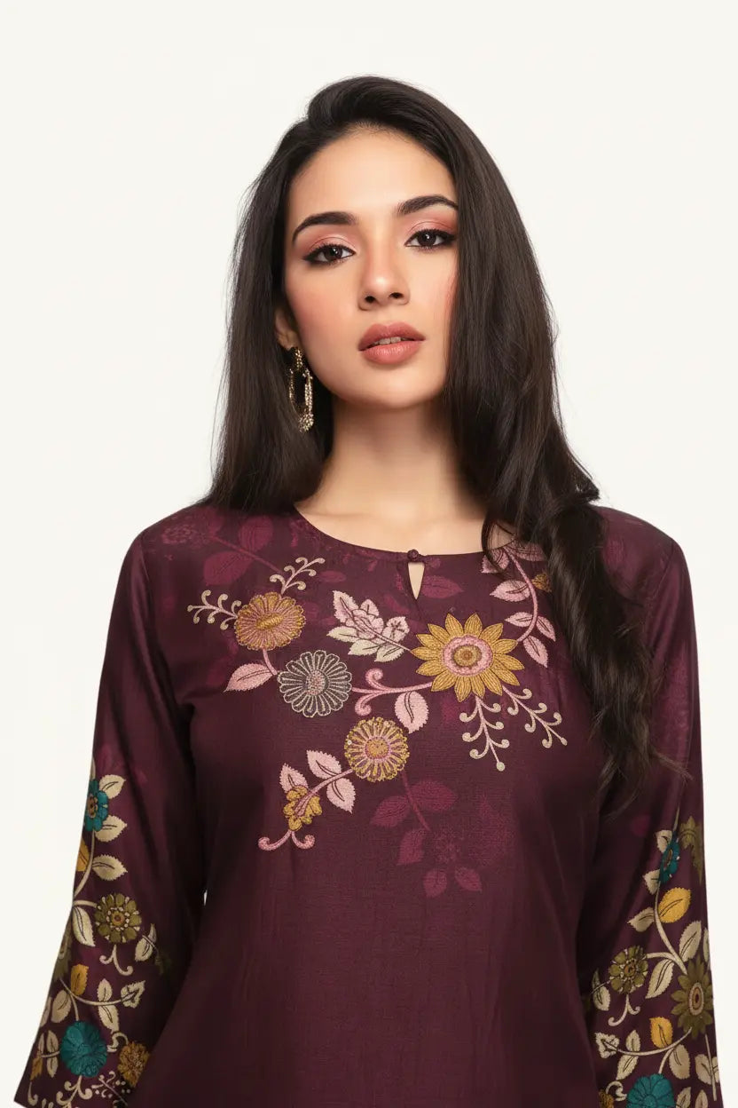 Woman wearing a maroon embroidered top with floral patterns on a white background