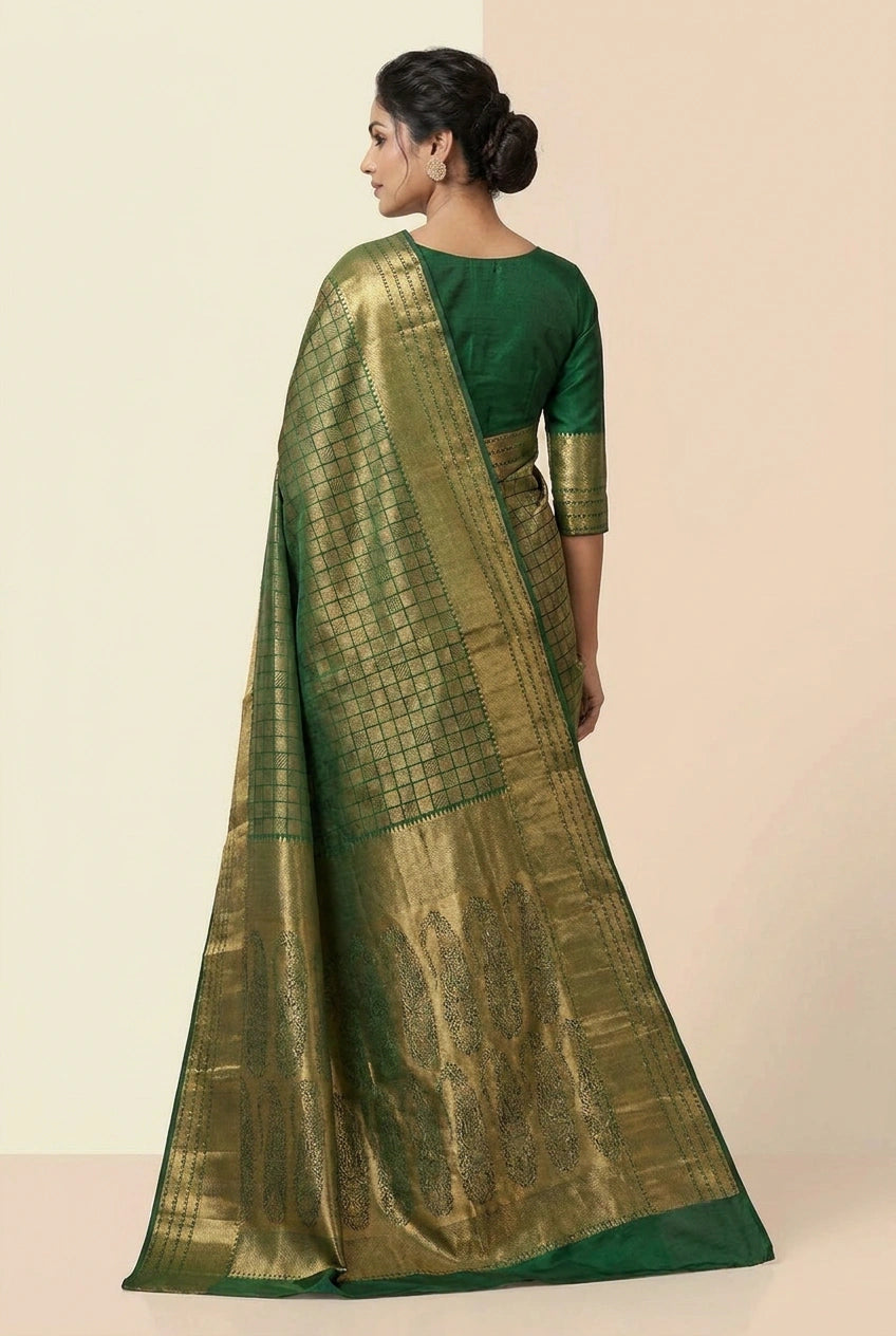 Woman wearing a green saree with a gold border on a beige background