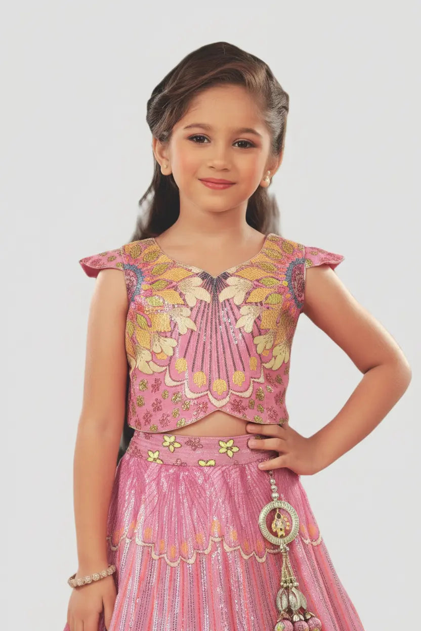 Young girl wearing a pink traditional outfit with floral patterns on a white background