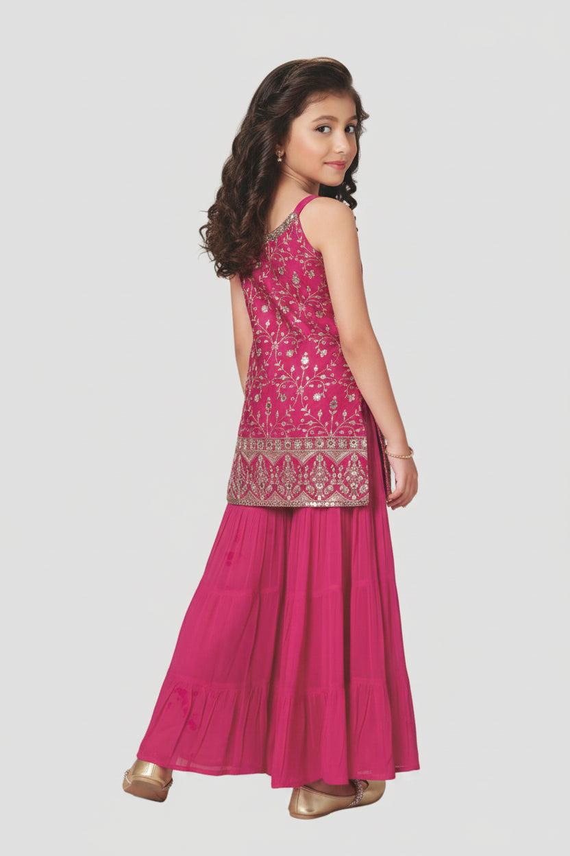 Young girl wearing a pink traditional outfit with intricate designs on a white background