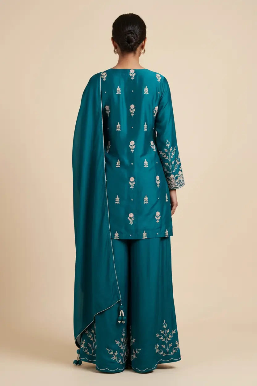 Teal traditional outfit with intricate patterns on a beige background