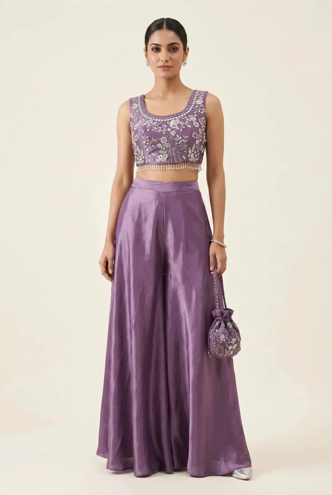 Woman wearing a purple outfit with a matching handbag on a plain background