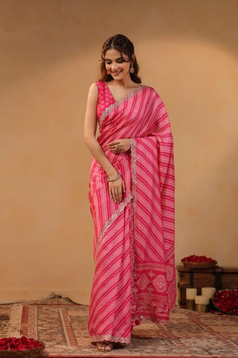 Woman wearing a pink saree with a patterned border against a beige background