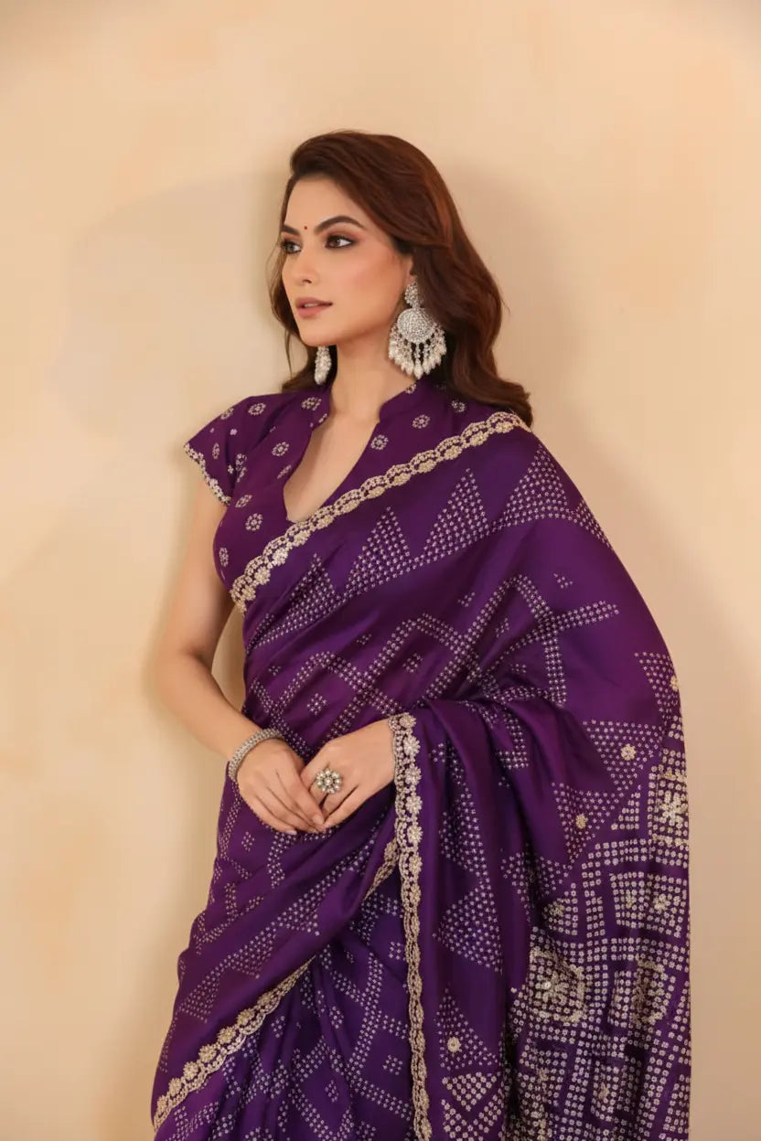 Woman wearing a purple saree with white patterns against a beige background