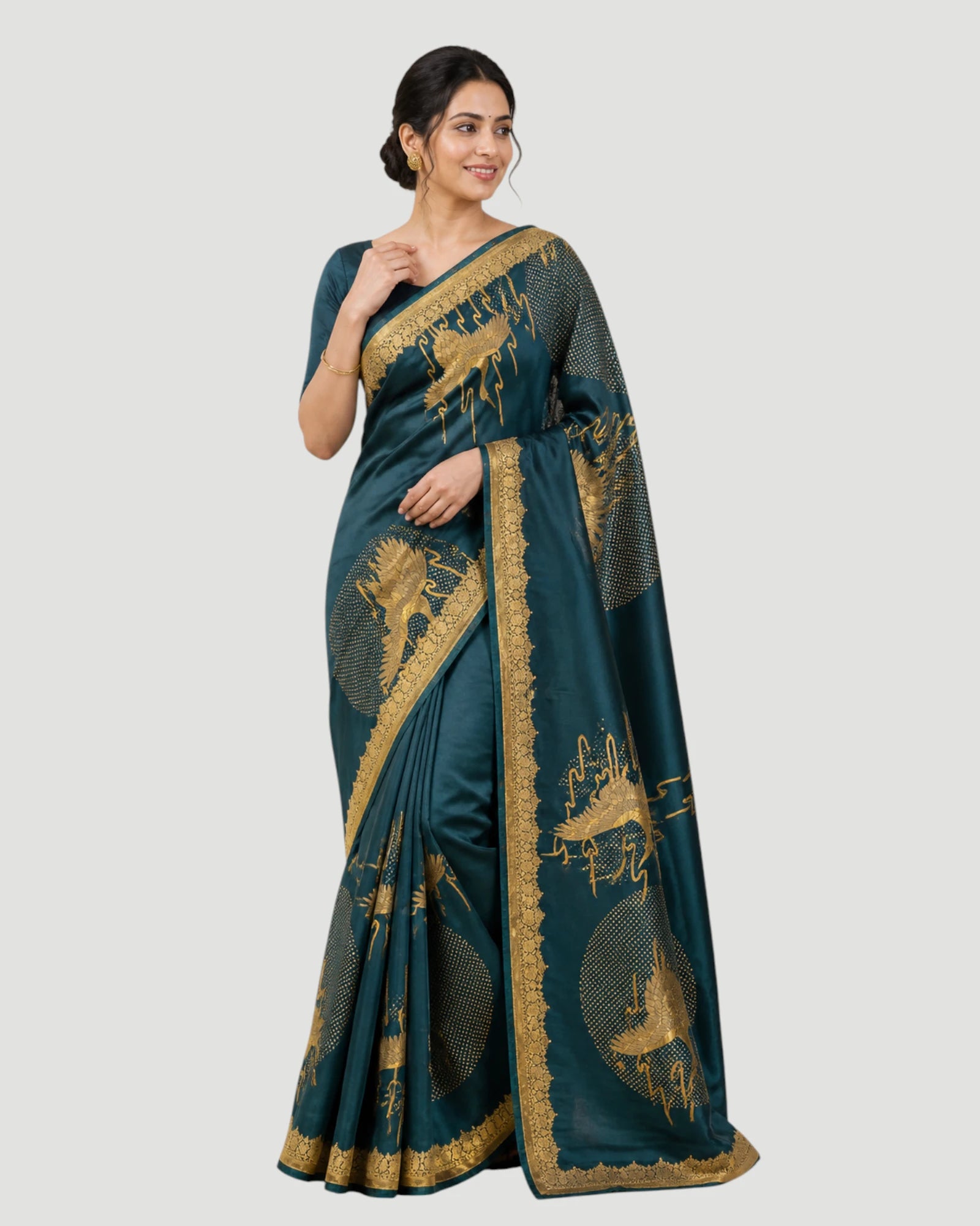 Woman wearing a teal saree with gold patterns on a white background