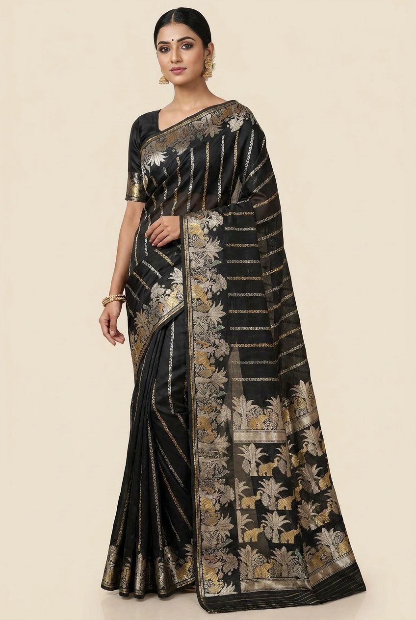 Woman wearing a black saree with gold floral patterns on a beige background