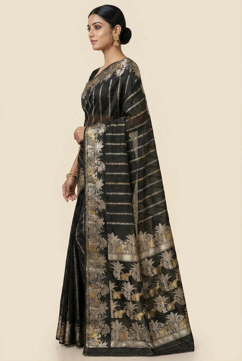 Woman wearing a black saree with gold patterns on a beige background