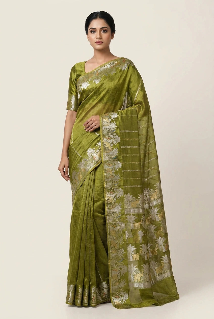 Woman wearing a green saree with a white floral pattern on a plain background