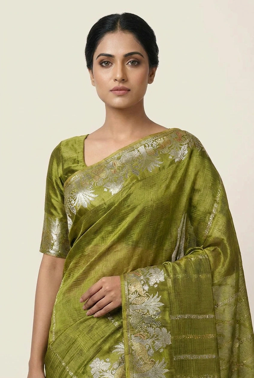 Woman wearing a green saree with floral patterns on a beige background