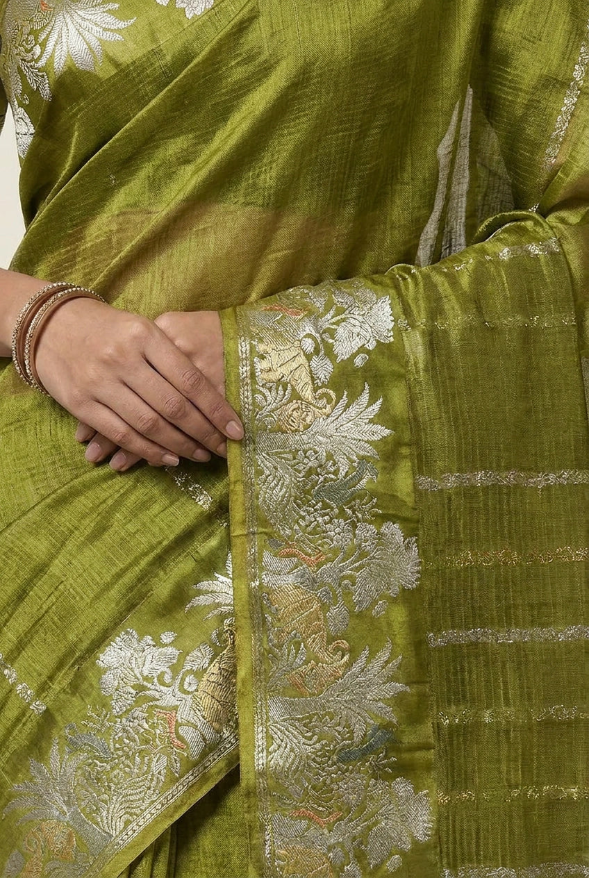 Green saree with floral patterns and a hand holding it