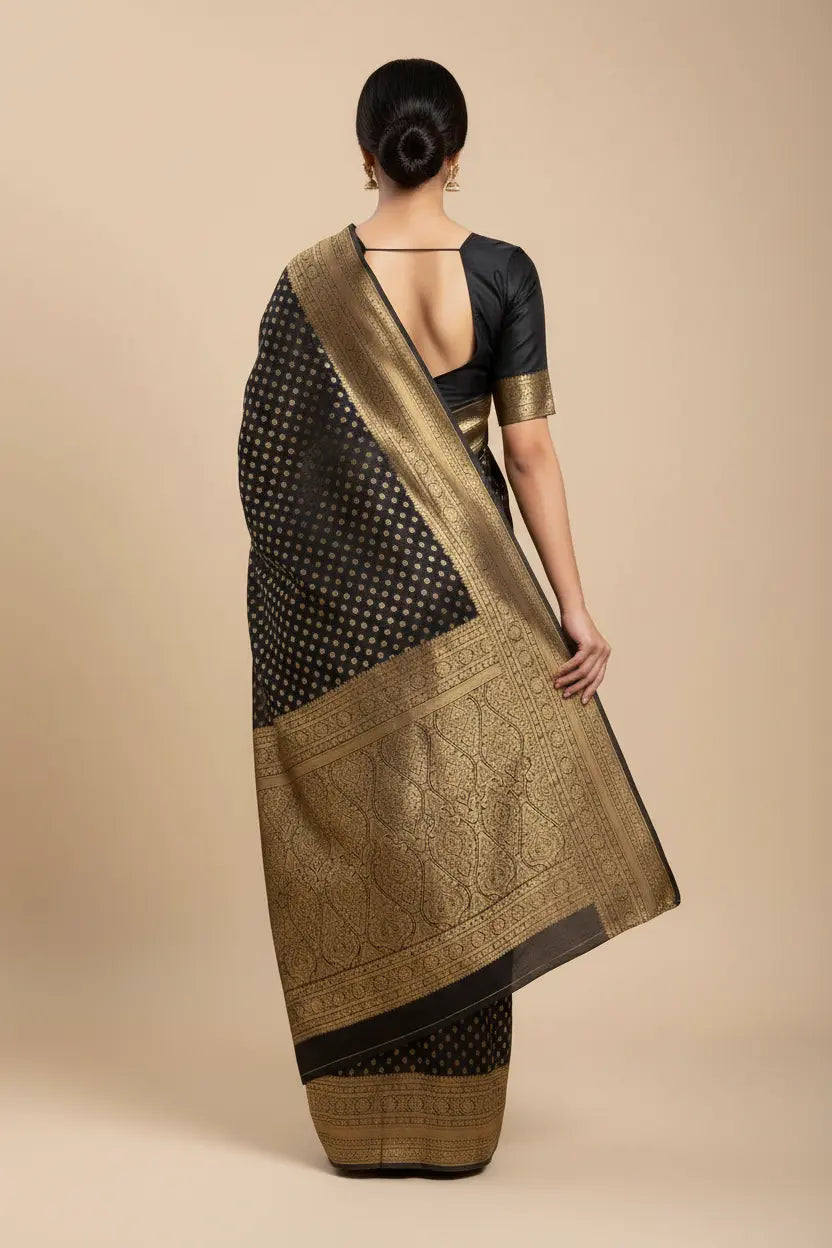 Woman wearing a black and gold saree on a beige background