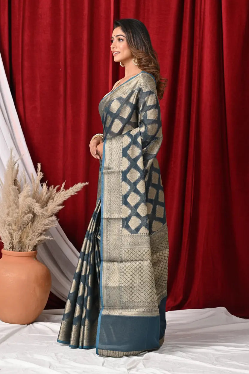 Woman holding a saree with a geometric pattern against a red curtain background