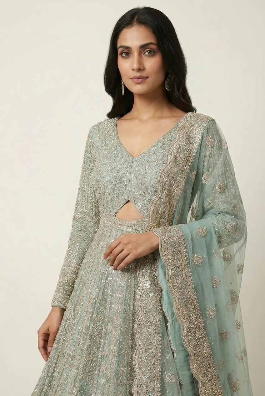 Woman wearing a light blue embroidered traditional outfit on a plain background