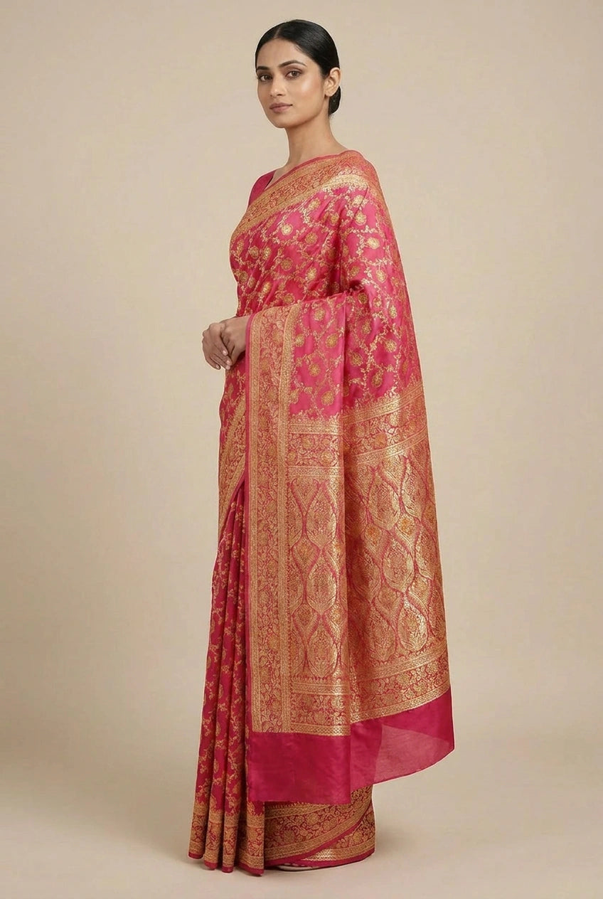 Woman wearing a pink saree with gold patterns on a beige background