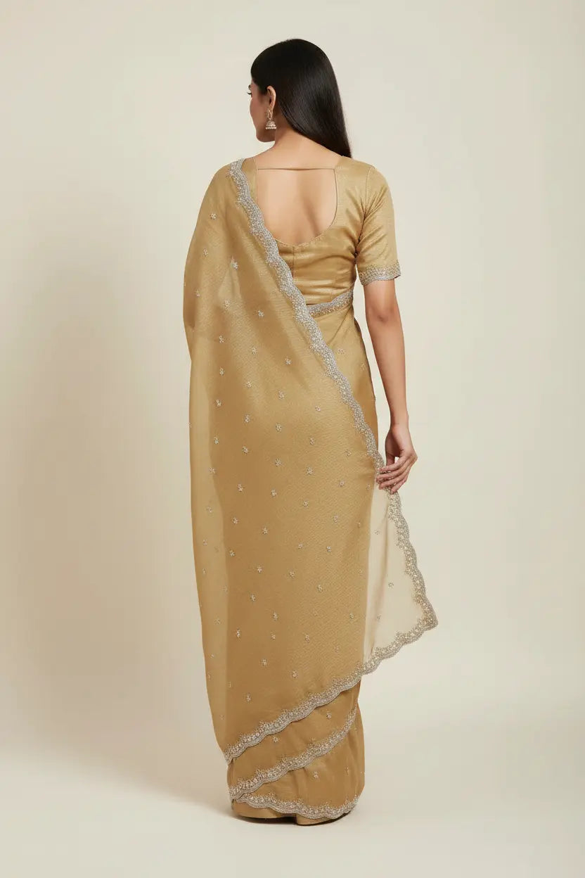 Woman wearing a beige saree with a subtle pattern on a plain background