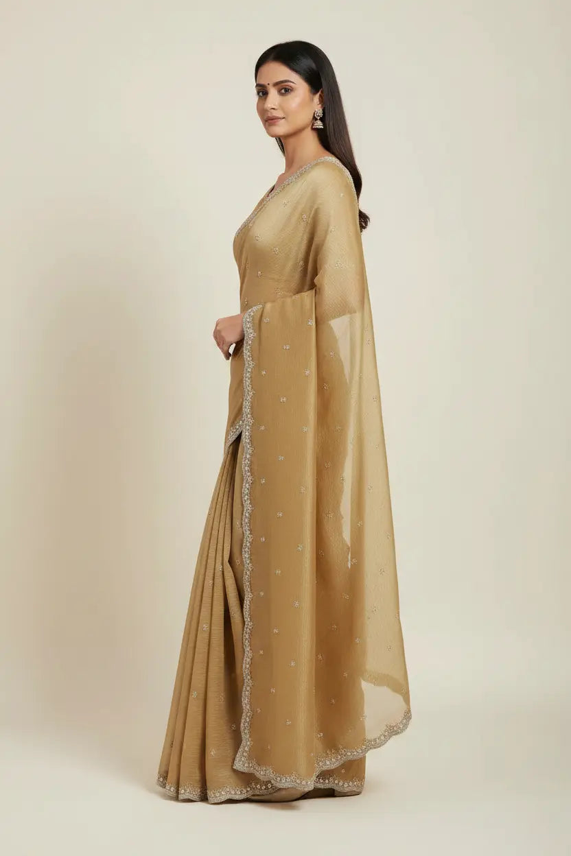 Woman wearing a beige saree with a plain background