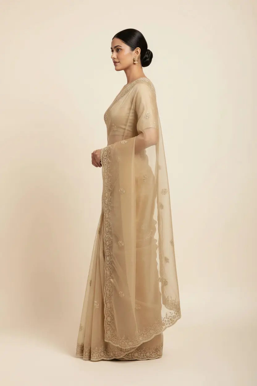 Woman wearing a beige saree with a plain background