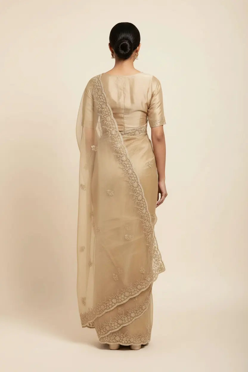 Woman wearing a beige saree with a plain background