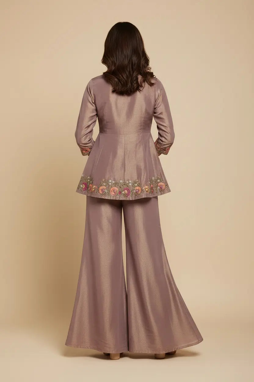 Woman wearing a mauve traditional outfit with floral embroidery on a beige background