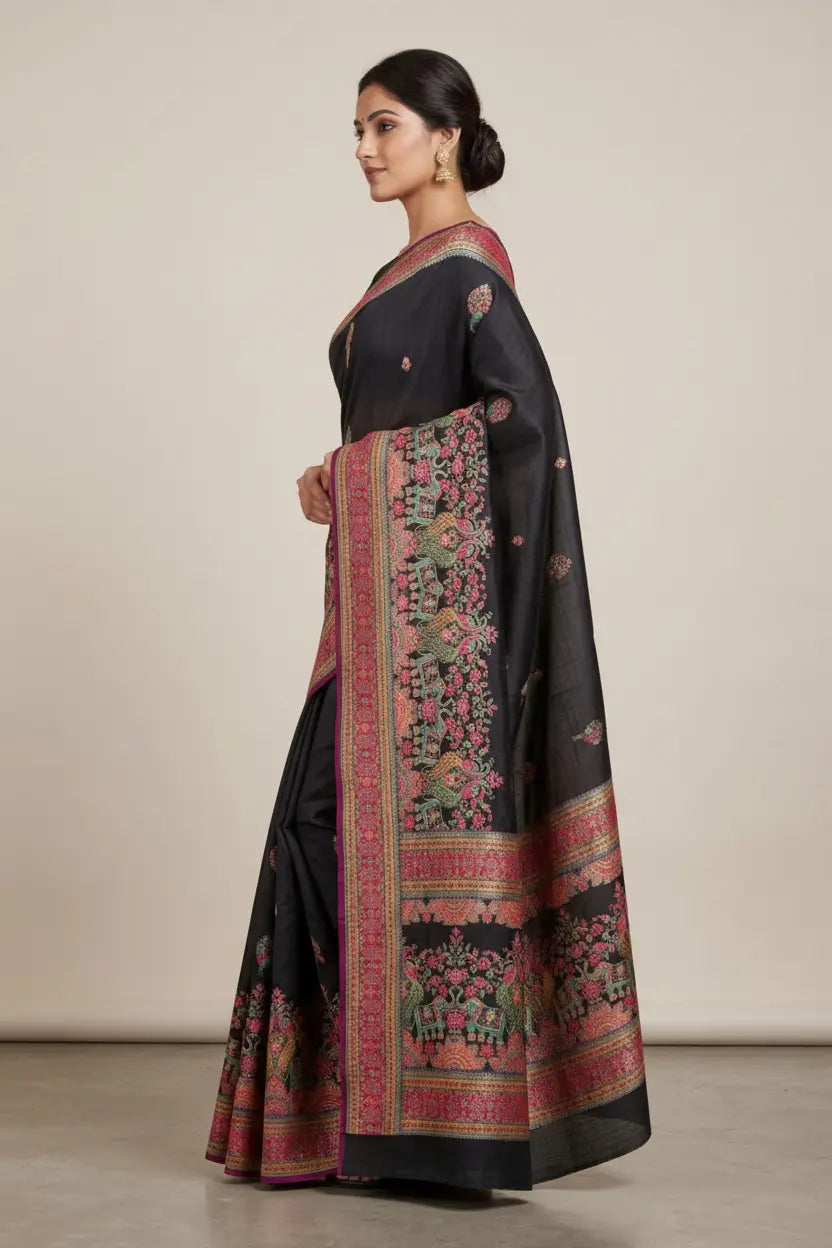 Woman wearing a black saree with floral patterns on a plain background
