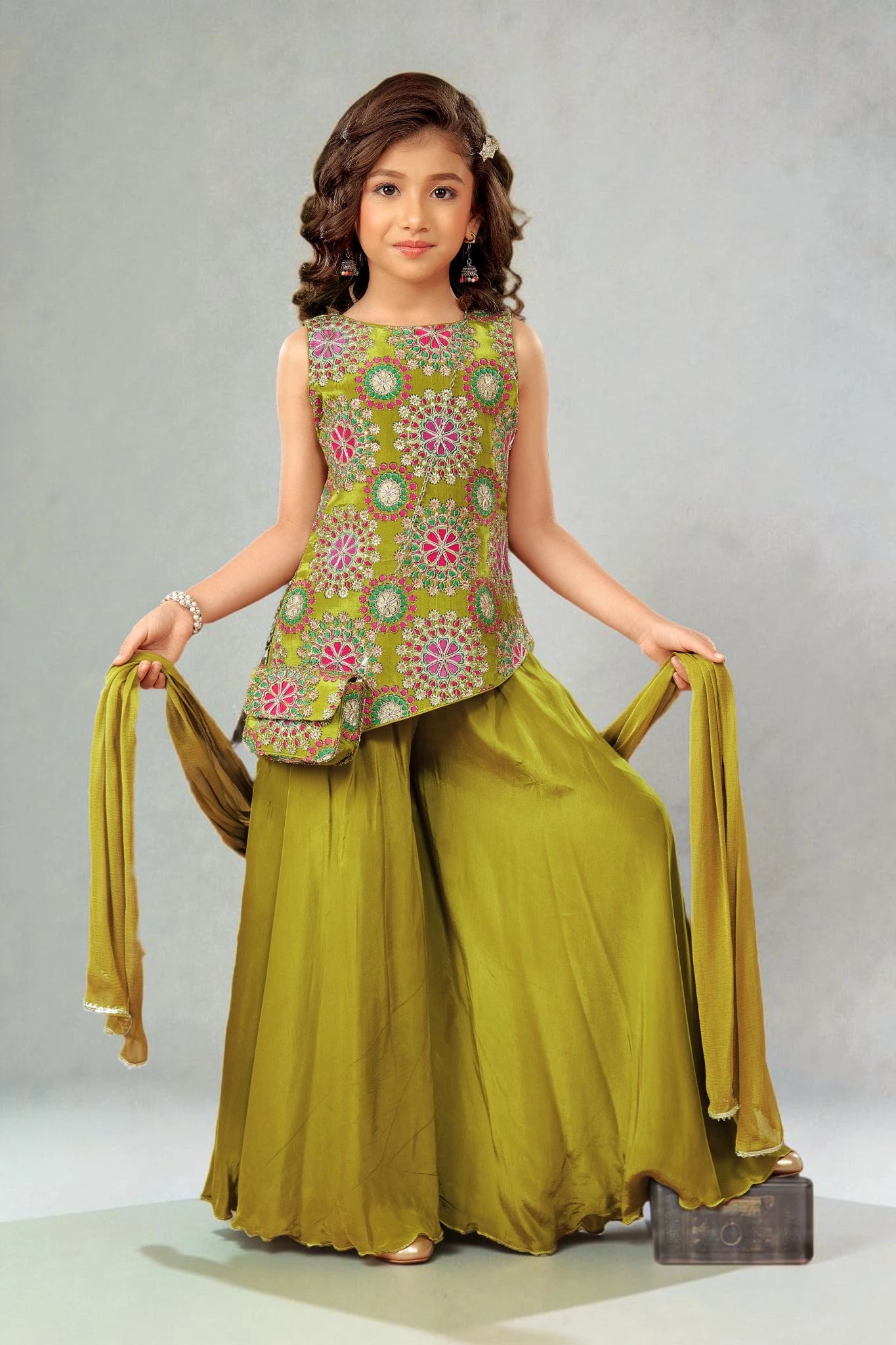 Young girl wearing a green traditional outfit with a floral top and long skirt on a gray background