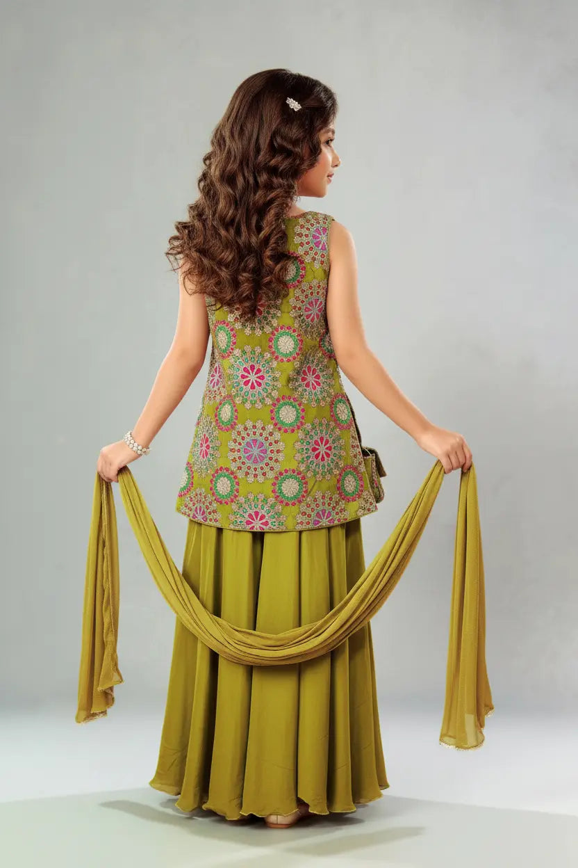 Woman wearing a green patterned top and skirt with a matching scarf on a gray background