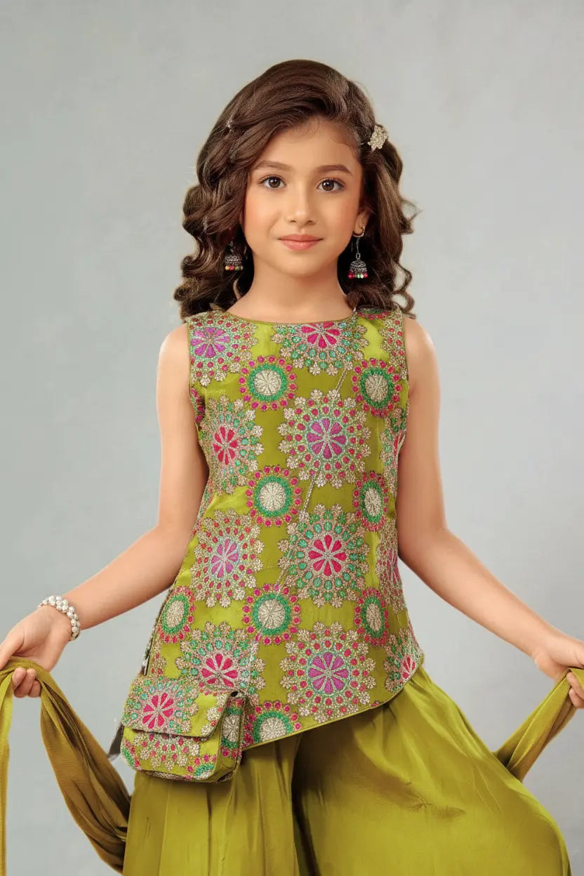 Young girl wearing a colorful top and green pants against a gray background