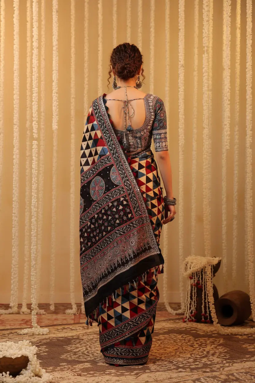 Woman wearing a patterned saree with a textured beige curtain background