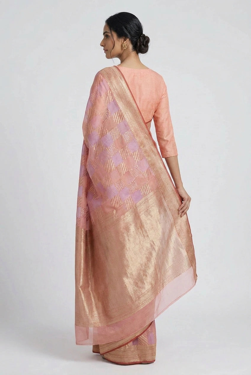 Woman wearing a peach saree with a subtle pattern on a white background