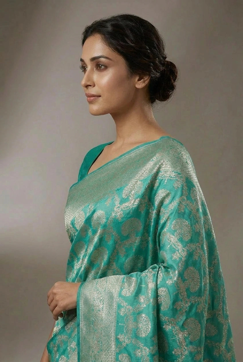 Woman wearing a green saree with a subtle pattern against a neutral background