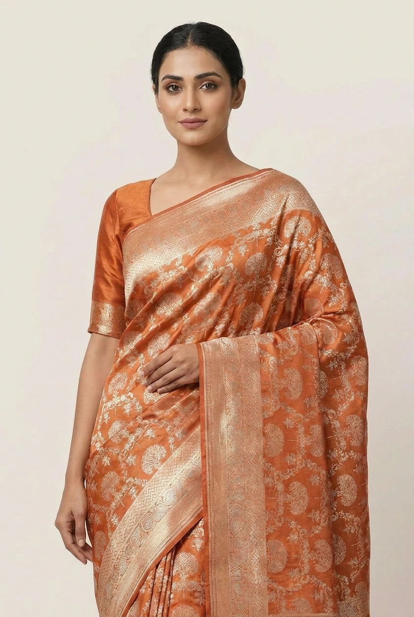 Woman wearing an orange saree with a subtle pattern on a plain background