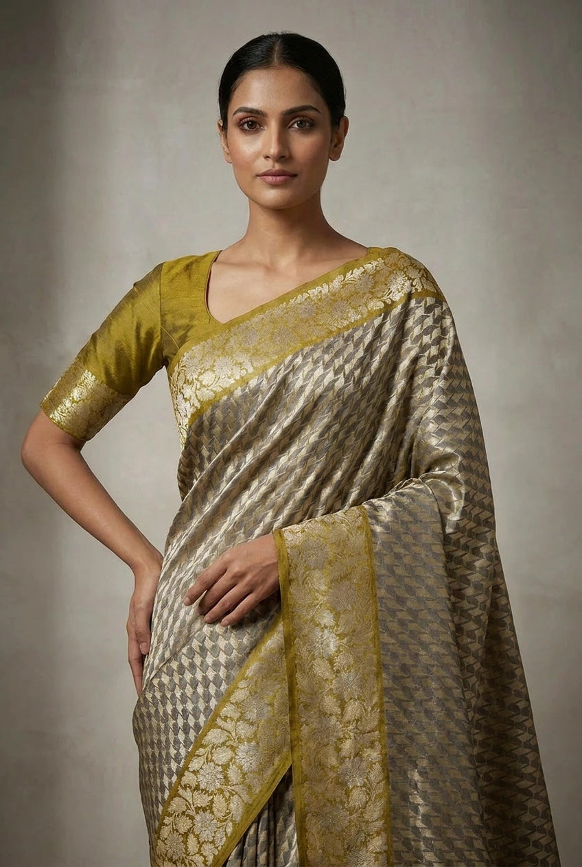Woman wearing a traditional saree with gold and silver patterns on a neutral background