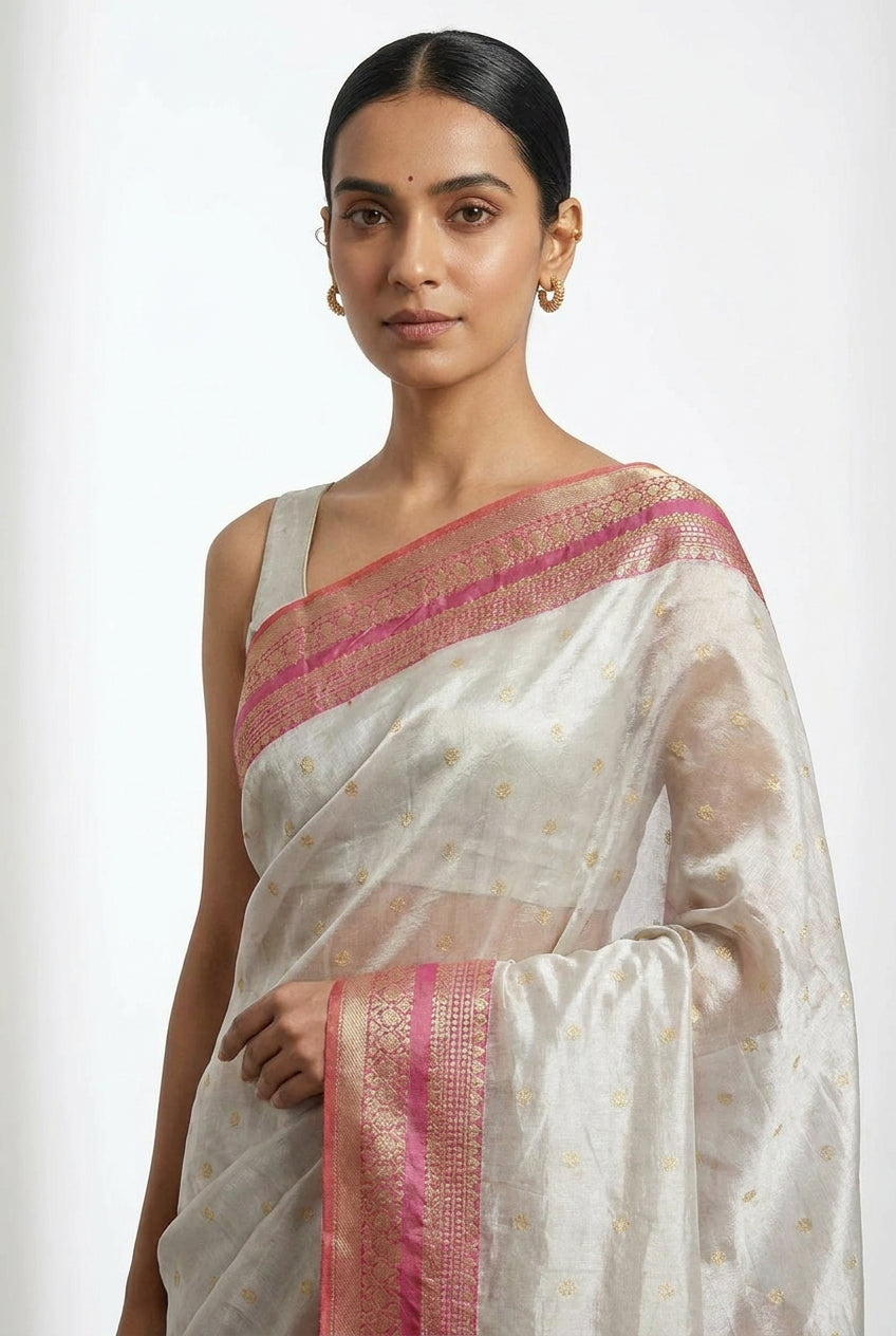 Woman wearing a white saree with pink border on a white background