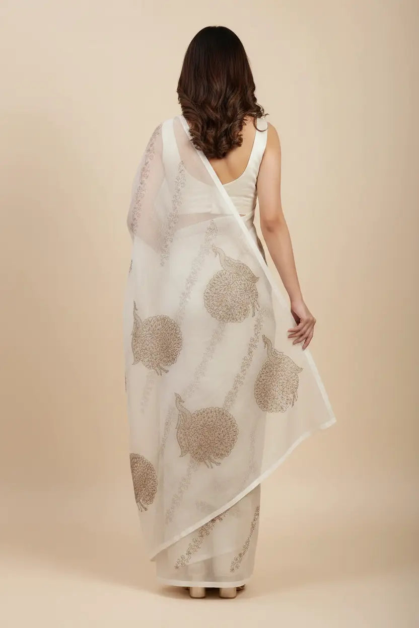 Woman wearing a beige saree with a floral pattern on a beige background