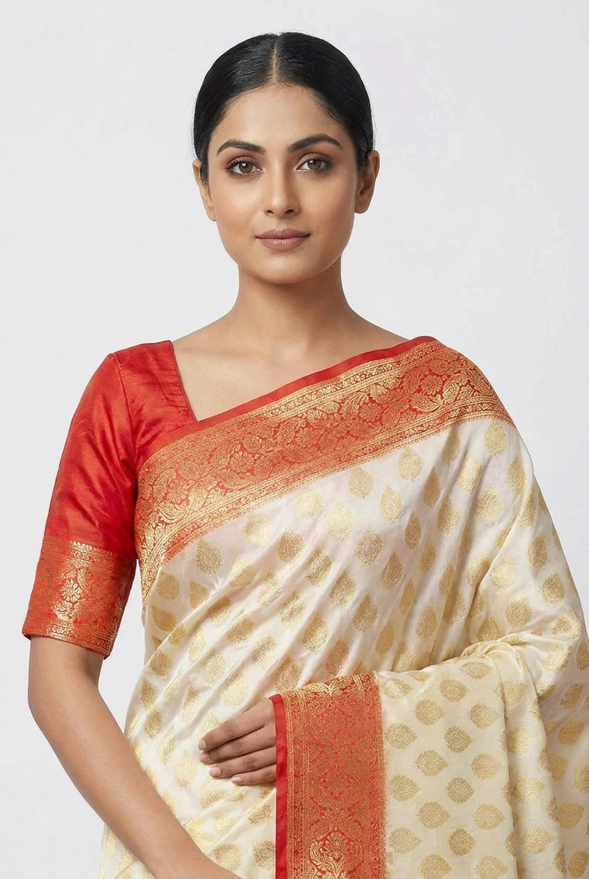 Woman wearing a traditional saree with red blouse and white and gold patterned body on a plain background