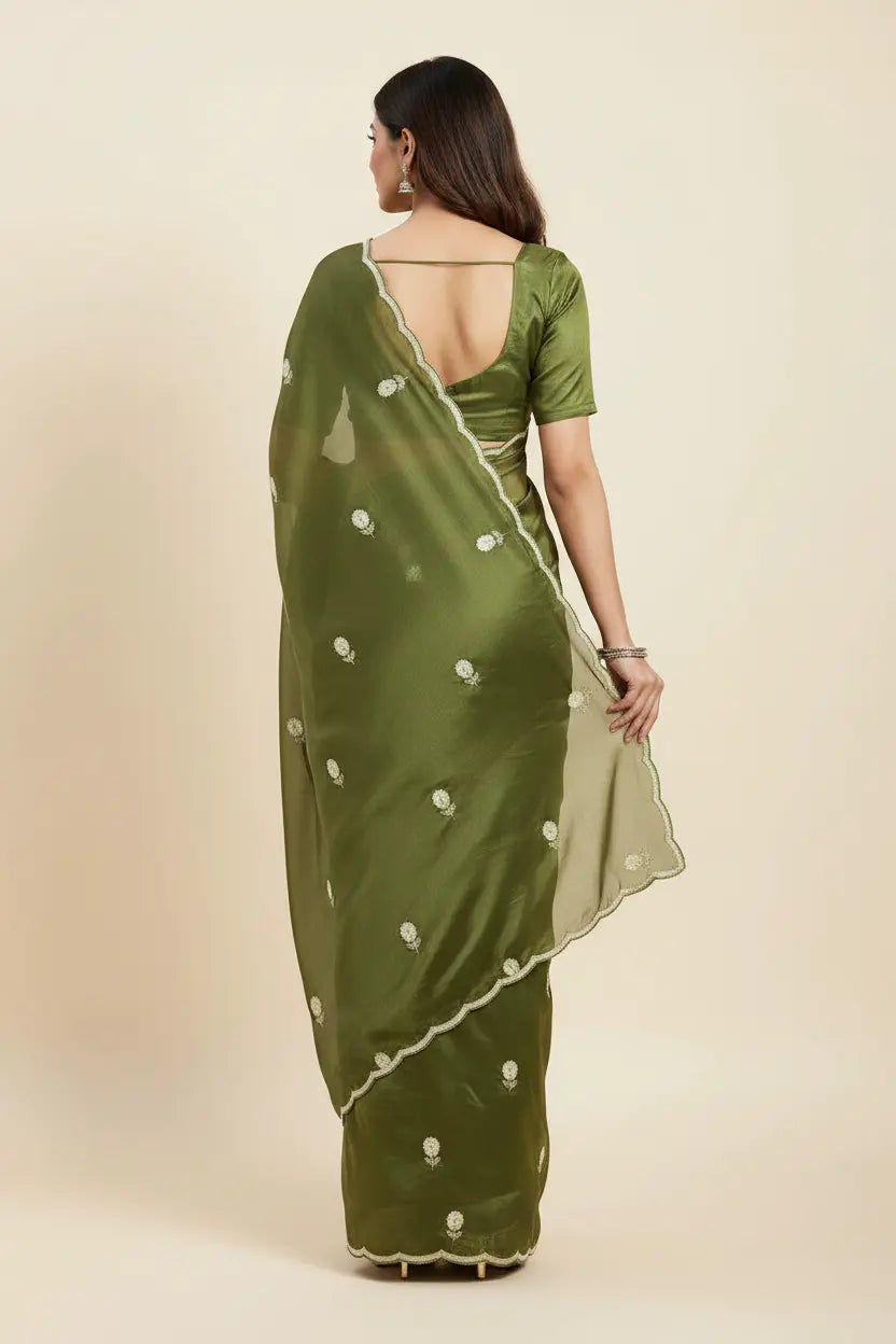 Woman wearing a green saree with white patterns on a beige background