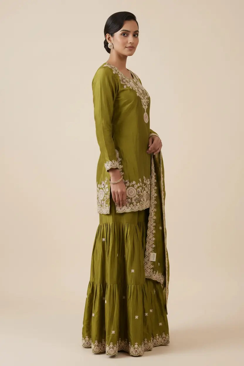 Woman wearing a green traditional outfit with embroidery on a beige background
