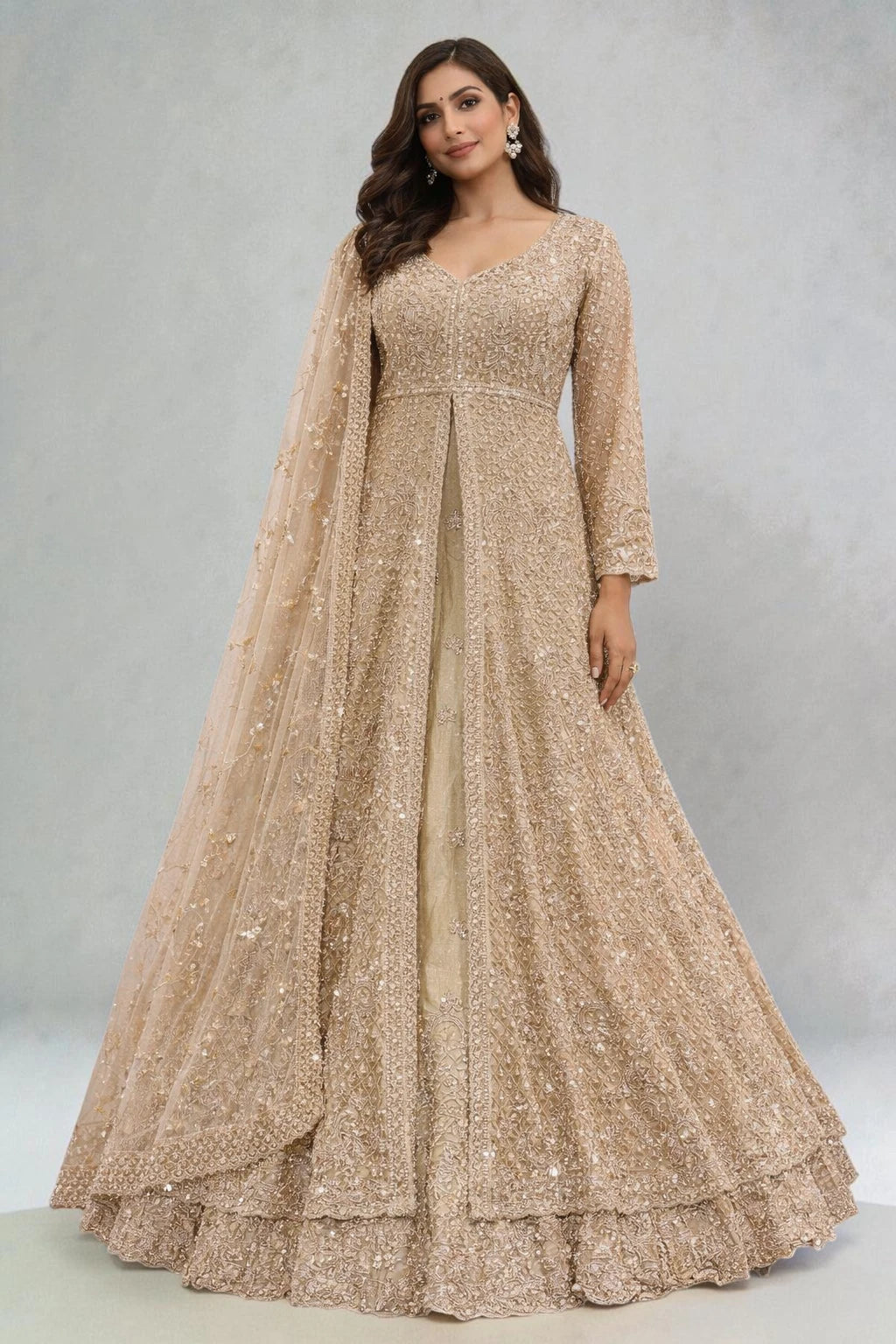 Woman wearing a long, beaded gold dress with a matching cape against a gray background