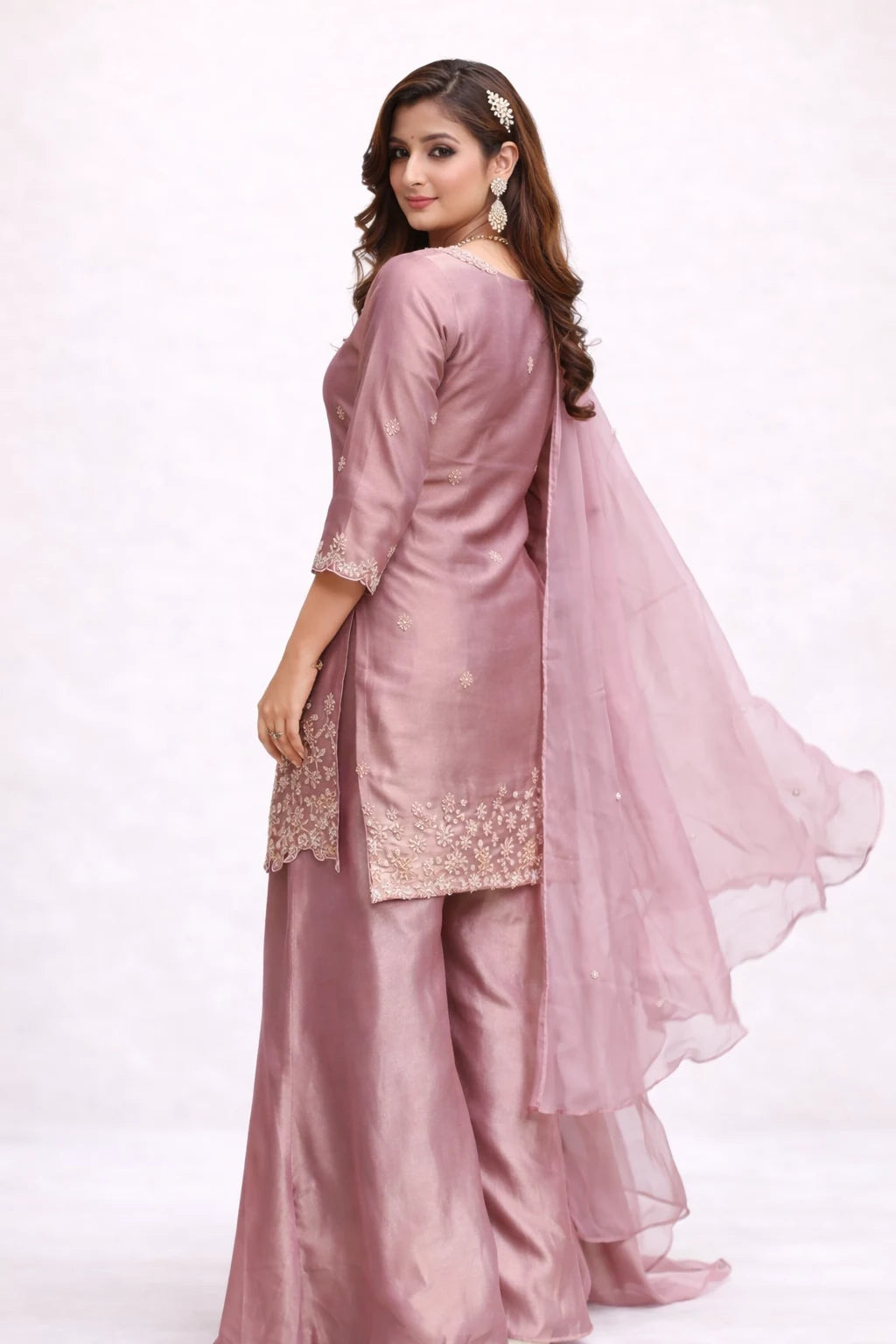 Woman wearing a pink traditional outfit with a matching dupatta on a white background