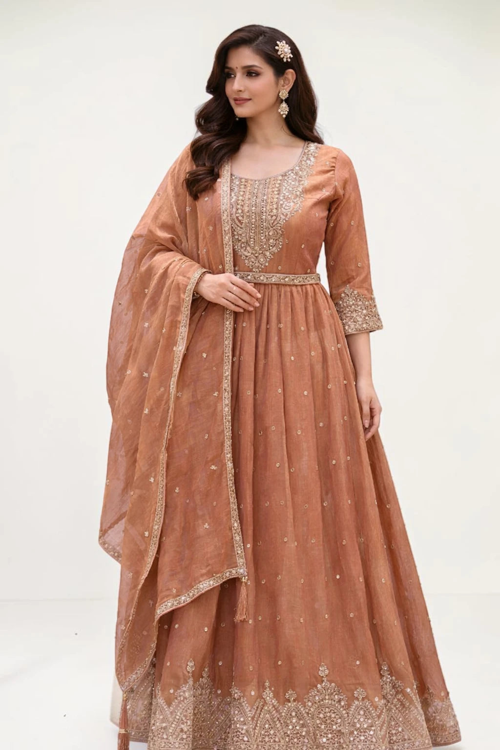 Woman wearing a brown traditional outfit with gold embroidery on a white background
