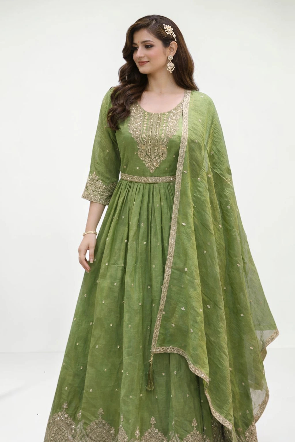 Woman wearing a green embroidered anarkali suit with a matching dupatta on a white background