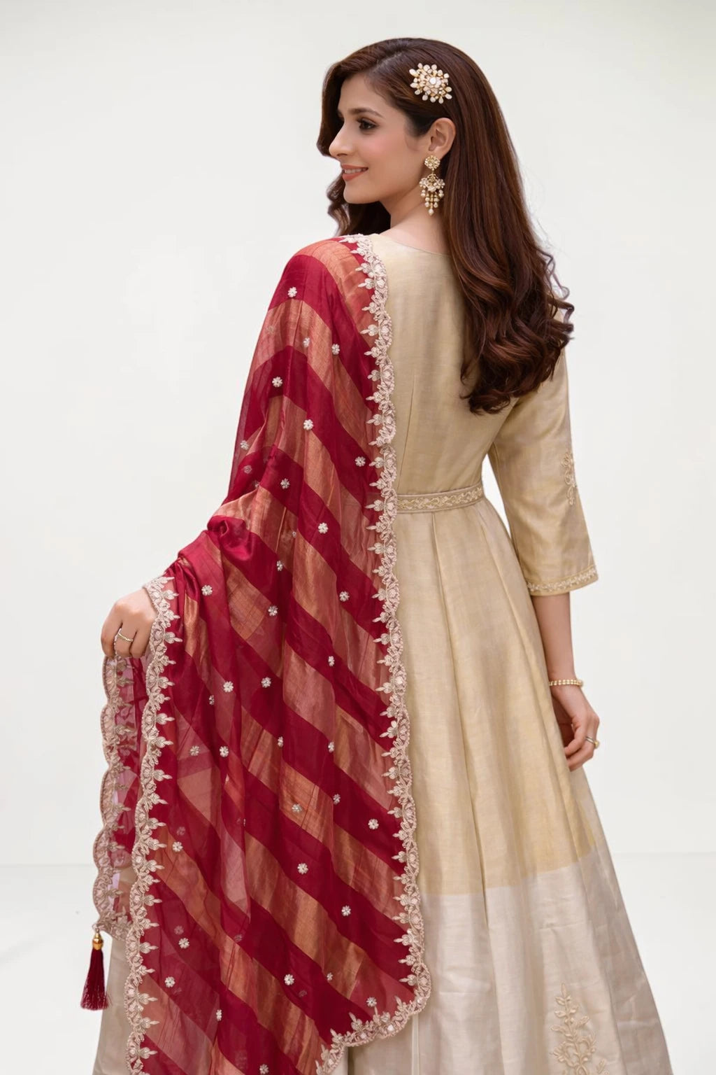 Woman wearing a beige dress with a red dupatta on a white background