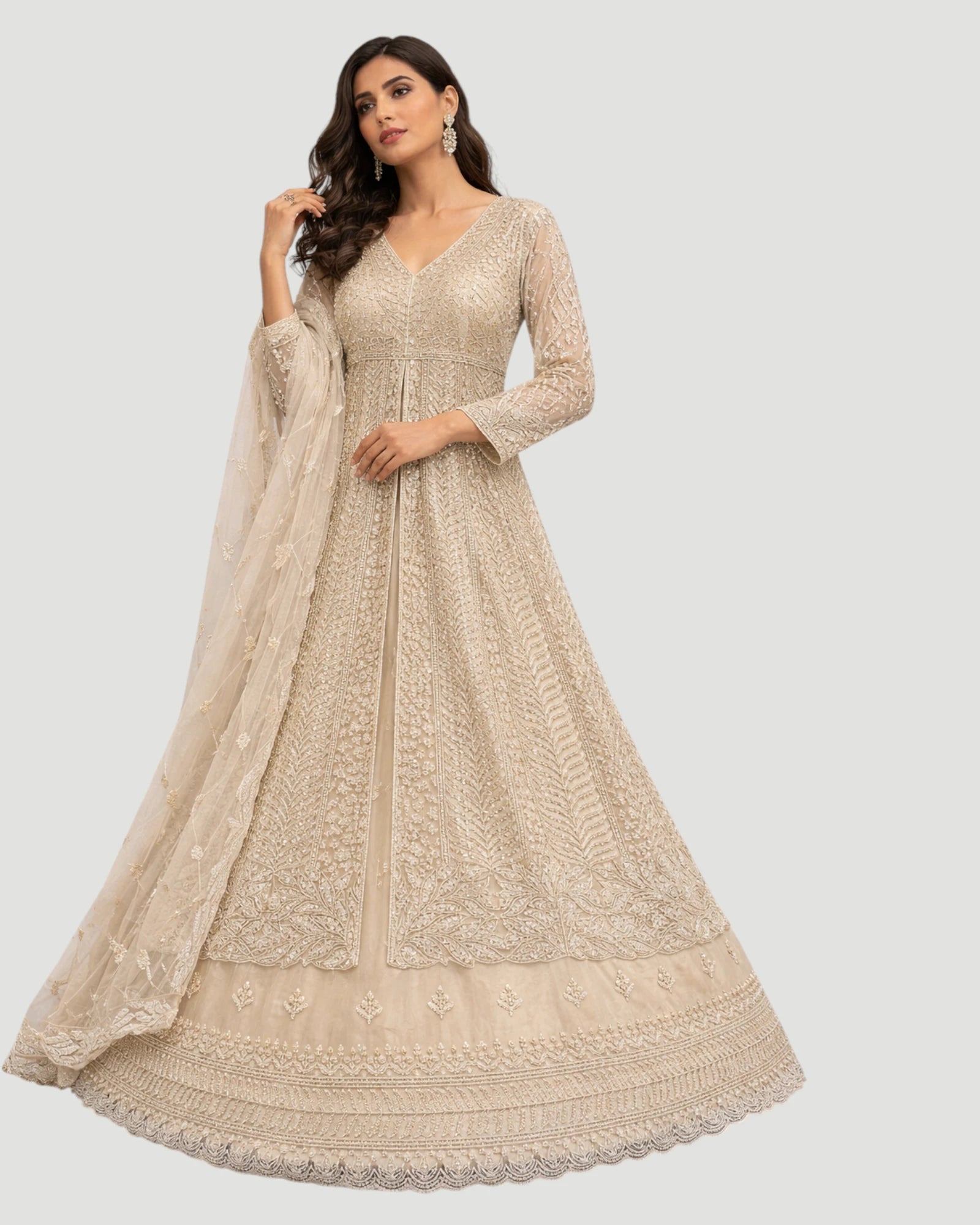 Woman wearing a beige embroidered anarkali suit with a matching dupatta on a light gray background