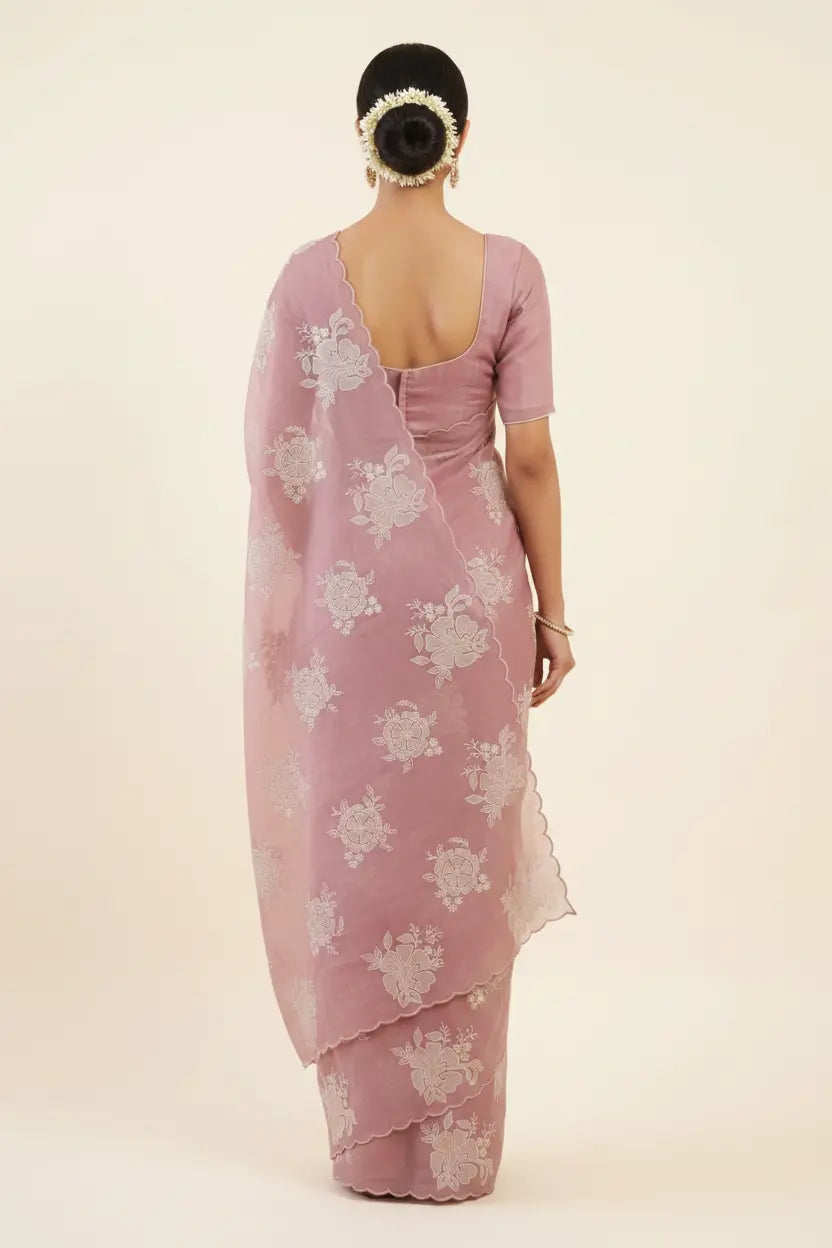 Pink saree with white floral patterns on a plain background