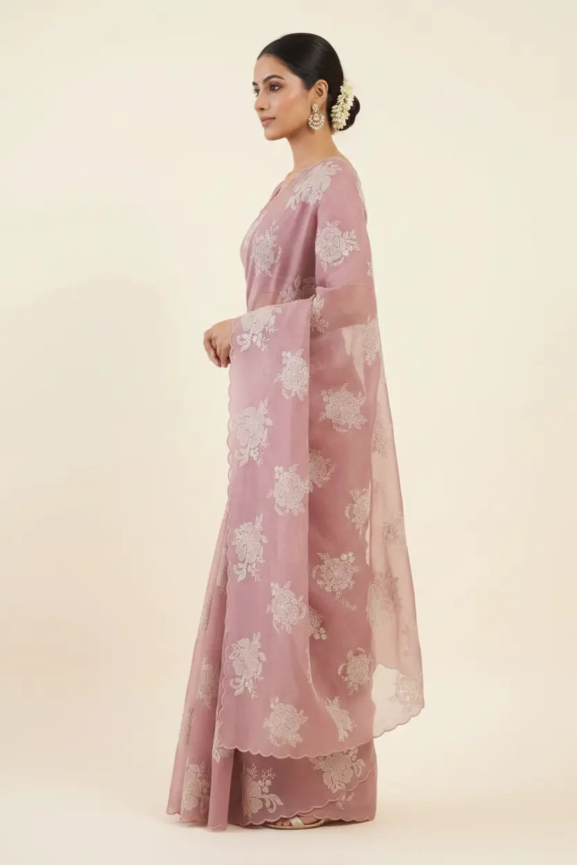 Woman wearing a pink saree with white floral patterns on a beige background