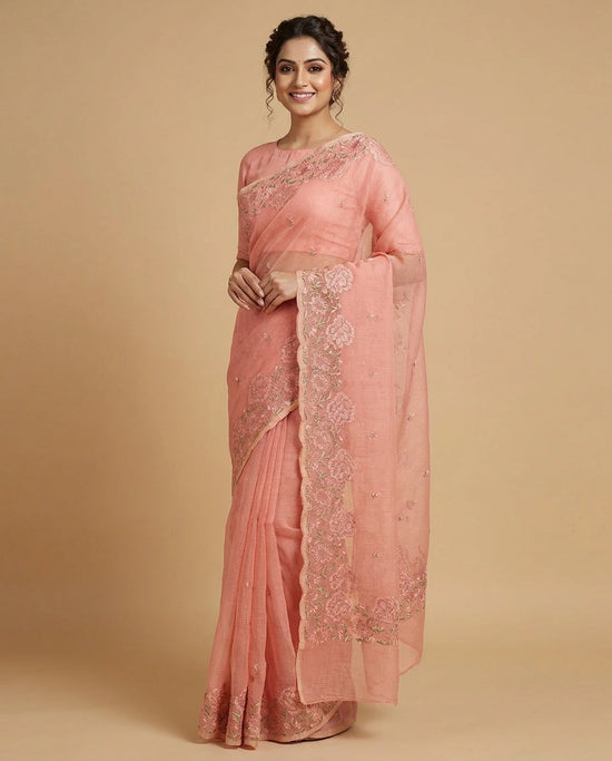 Woman wearing a pink saree with intricate designs on a beige background