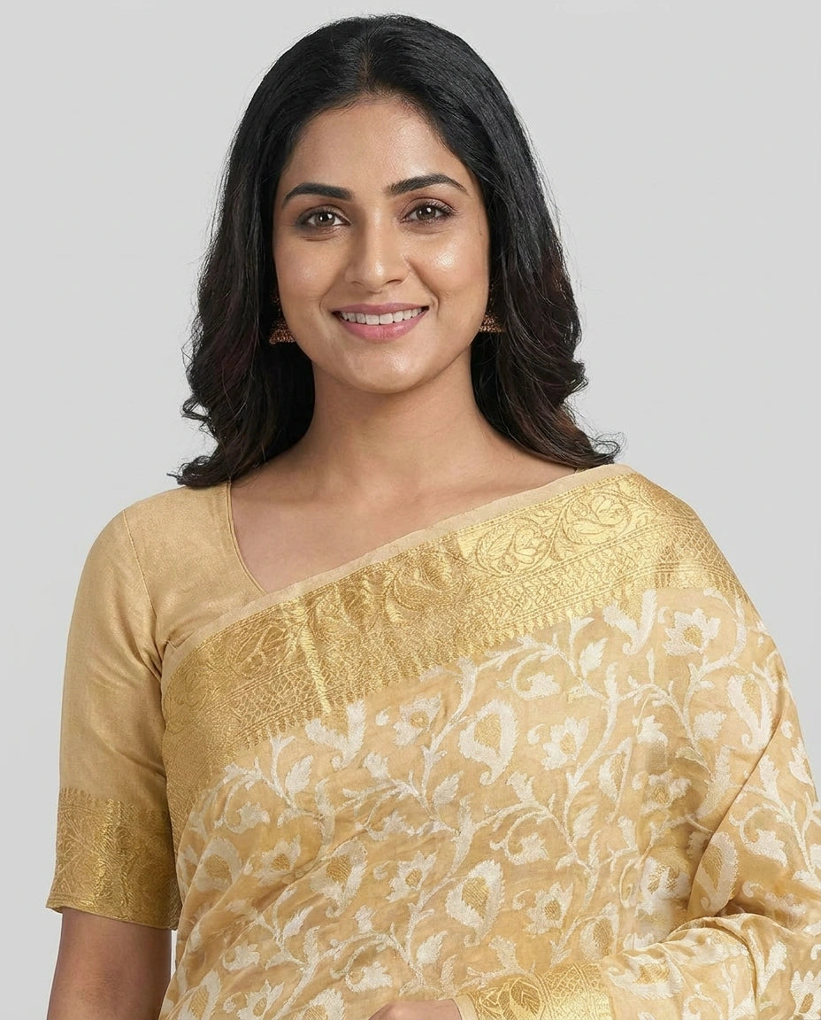 Woman wearing a gold and white saree against a gray background