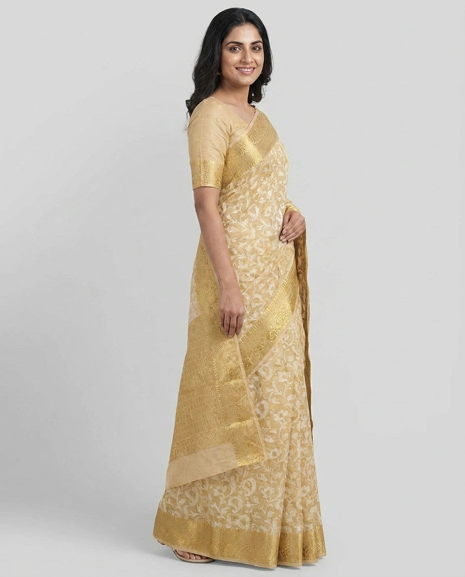 Woman wearing a gold saree with a white blouse on a gray background