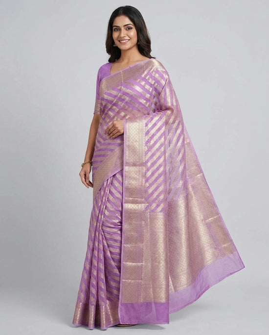Woman wearing a purple and gold saree on a gray background